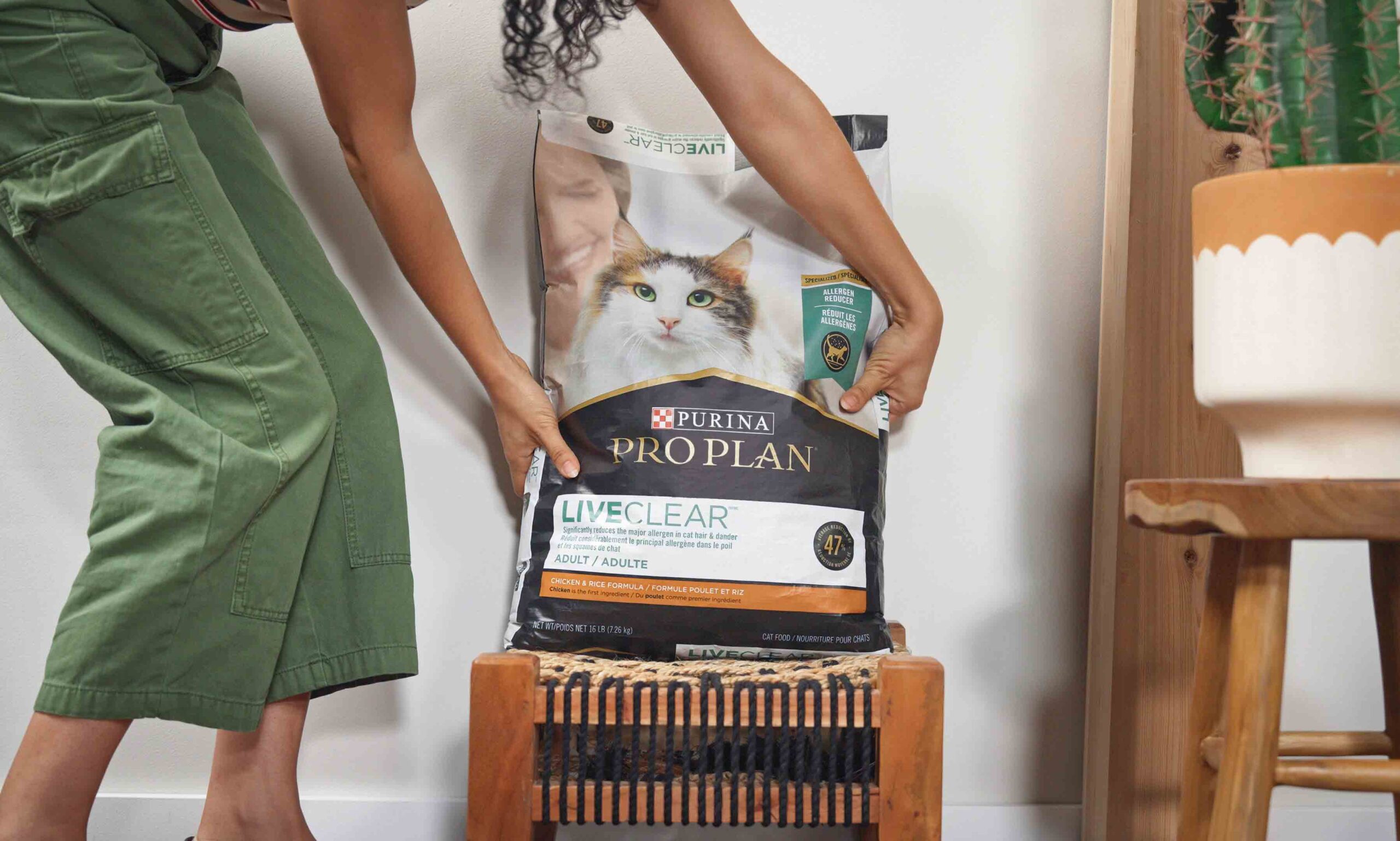 صورة امرأة تضع كيسًا من طعام القطط Purina LiveClear على طاولة